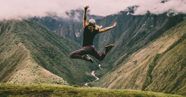 woman jumping on green mountains