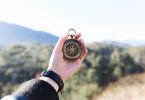 person holding compass selective focus photography