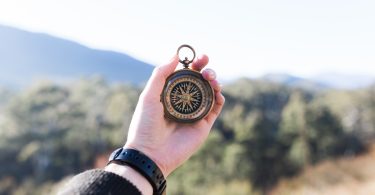 person holding compass selective focus photography