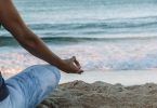 person in blue shorts sitting on beach shore during daytime