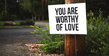 you are worthy of love sign beside tree and road