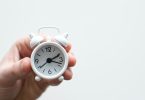 person holding white mini bell alarmclock