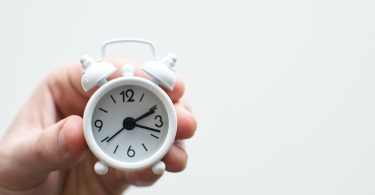 person holding white mini bell alarmclock