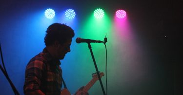 man playing guitar with stage lights