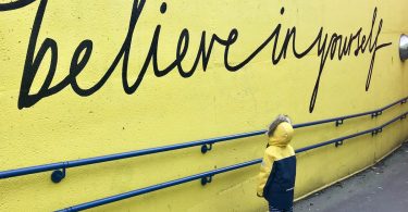 toddler looking at believe in yourself graffiti