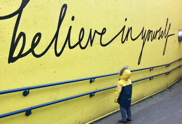 toddler looking at believe in yourself graffiti
